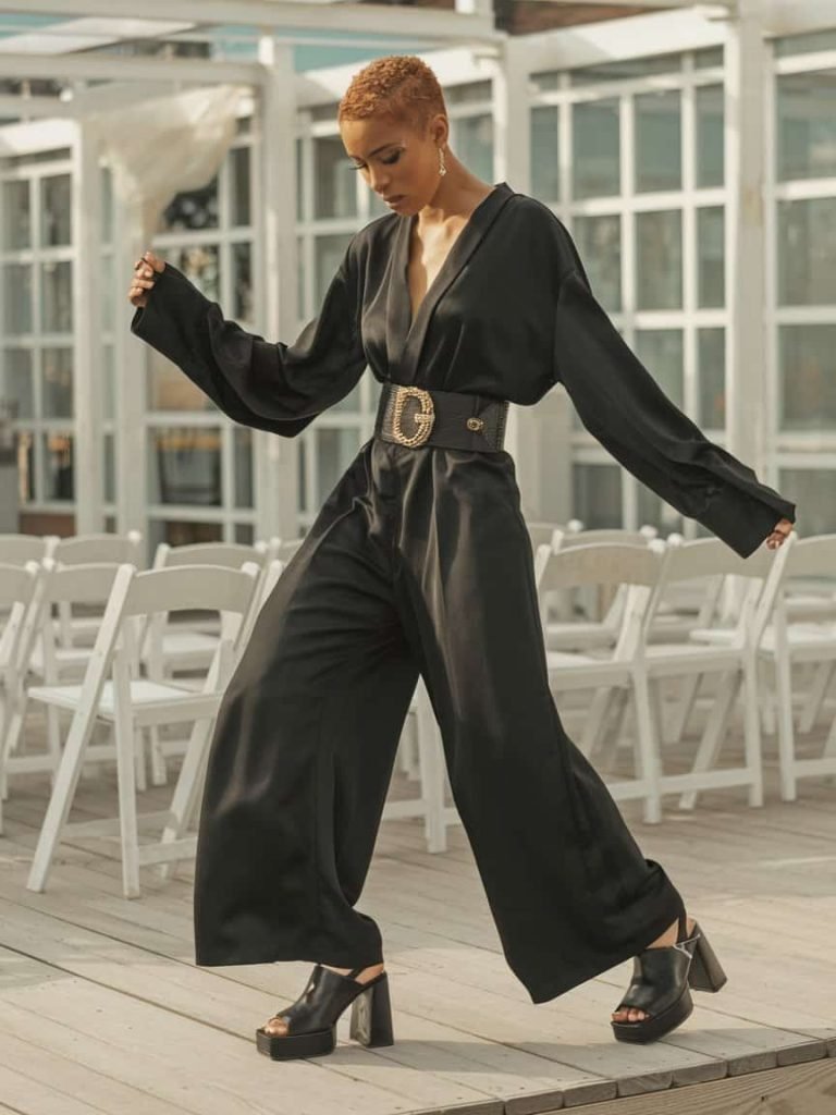 Elegant black jumpsuit with a bold belt showcases modern Black Tie Wedding Guest Dresses option.
