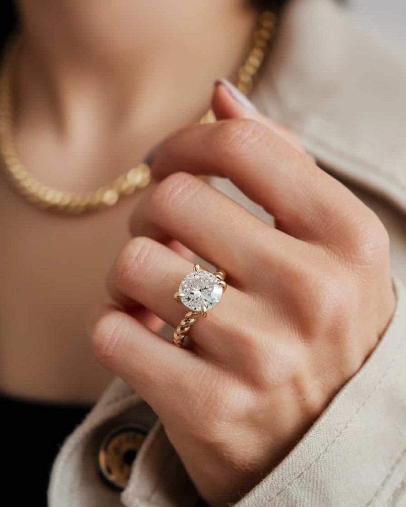 A collection of modern gold rings featuring geometric designs, arranged in a playful manner on a marble surface, showcasing their bold and artistic appeal.