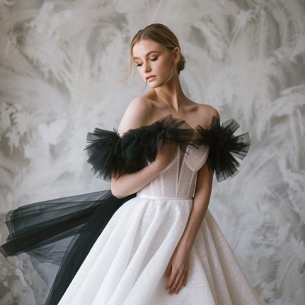 Romantic black and white wedding dresses with black tulle overlay on a flowing white A-line gown for a soft yet edgy look.