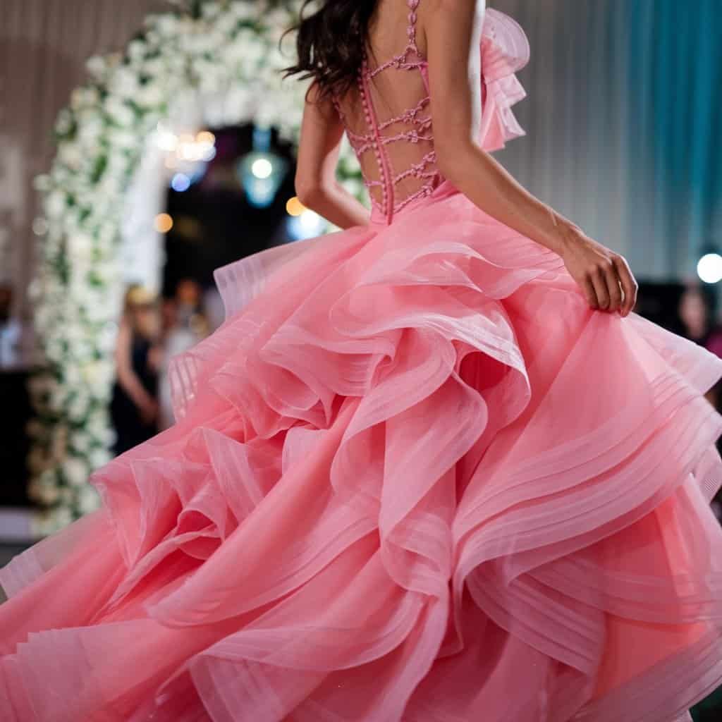 Bride dancing in a vibrant hot pink blush wedding dress, with cascading layers and flirty design elements.