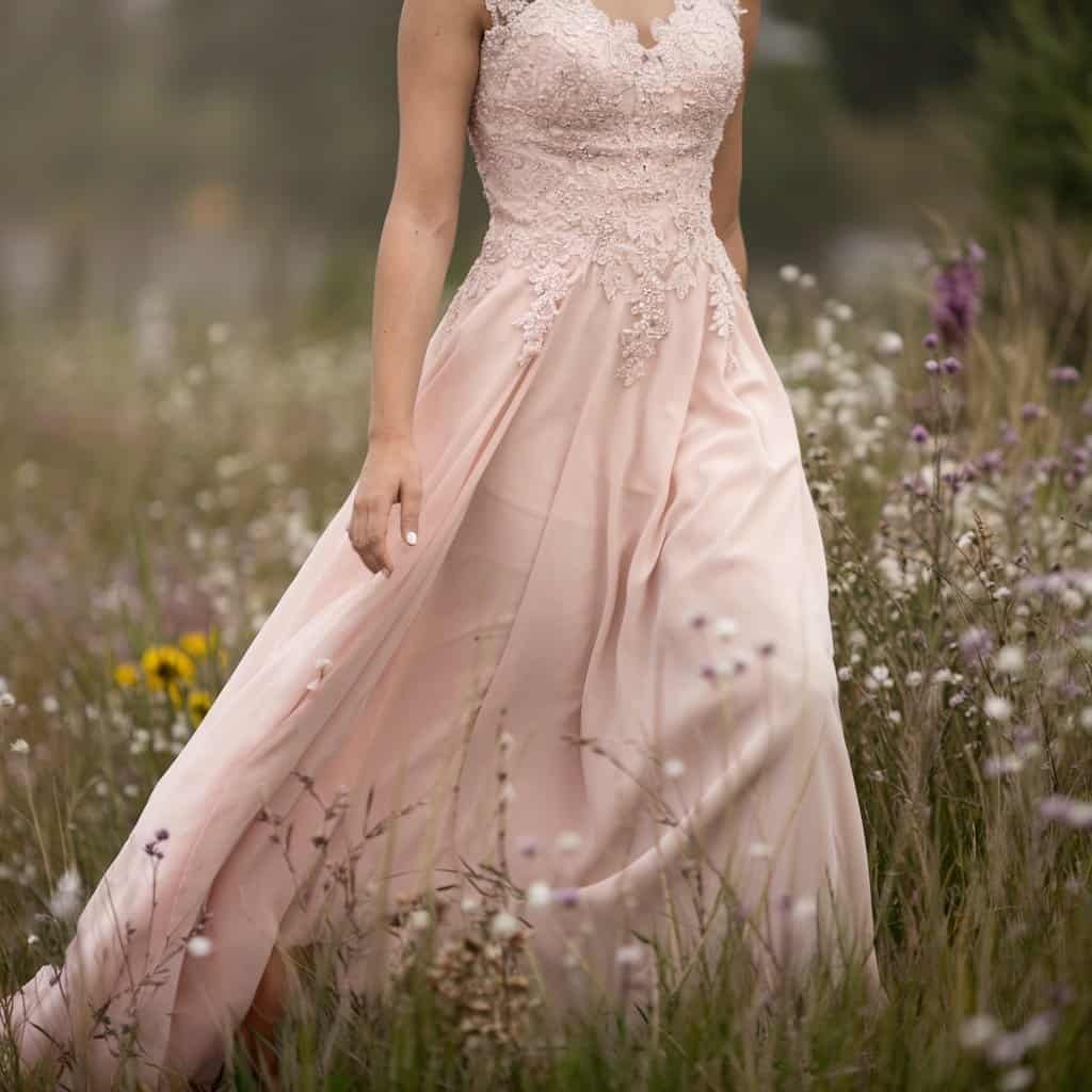 A fairy-tale-inspired blush wedding dress in pastel pink, perfect for an intimate garden ceremony.