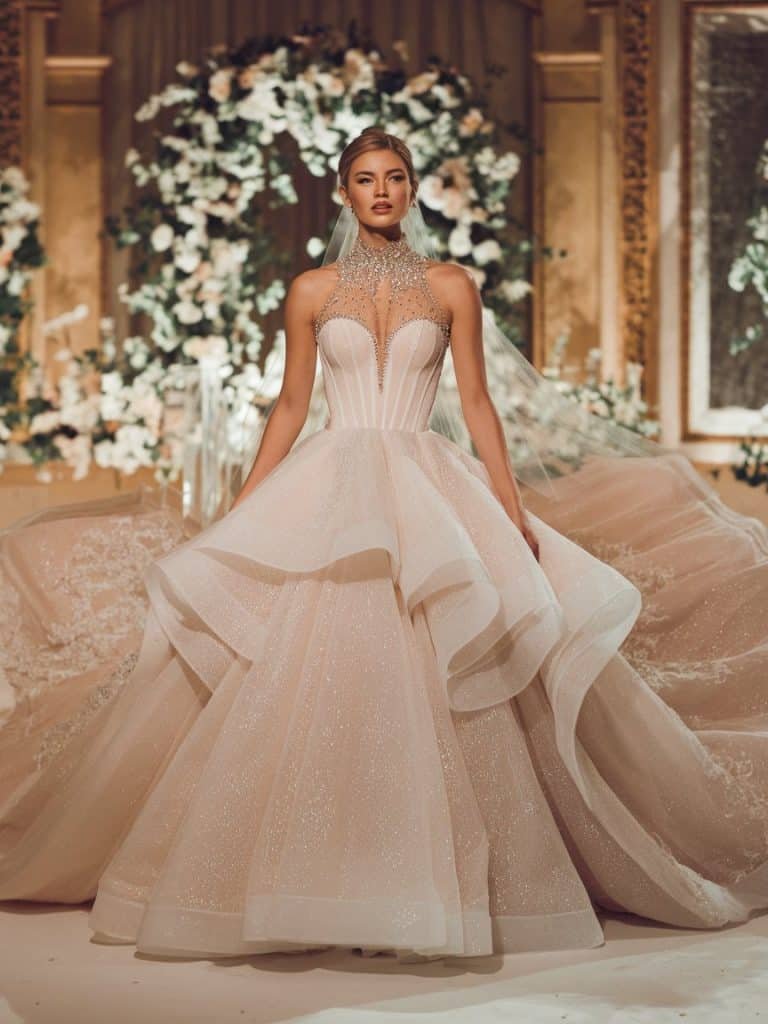 Dramatic high-neck wedding dress with voluminous tulle layers, offering a fairy tale-inspired bridal look