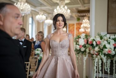 Close-up of a stylish woman wearing a chic cocktail dress in front of a large ‘15’ graphic, set against an elegant wedding ceremony backdrop, highlighting the ‘15 Latest Cocktail Dresses for Weddings in 2025.’