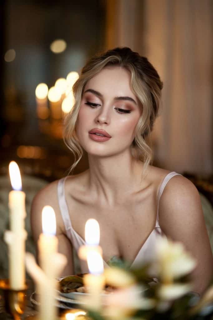 Close-up of soft curls and nude makeup paired with a beautiful Valentine's Day dress in a cozy restaurant