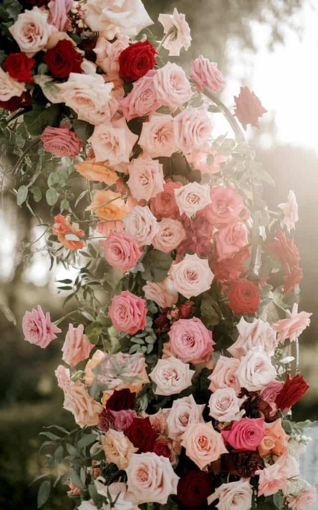 Stunning wedding arch adorned with a mix of red and pastel roses, creating a refined, elegant backdrop for vows.
